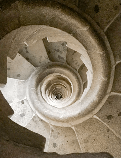 De stenen wenteltrap, van bovenaf gezien, creëert een hypnotiserend, tunnelachtig effect. Het beeld straalt diepte en een gevoel van architectonische schoonheid uit.